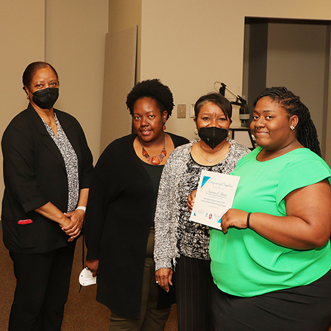 Four black female CHWs holding a certificate of compettion